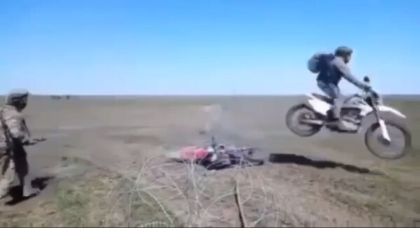 오토바이를 탄 러시아 보병이 우크라이나 측이 설치한 철조망을 뛰어넘는 장면/텔레그램 영상 캡처